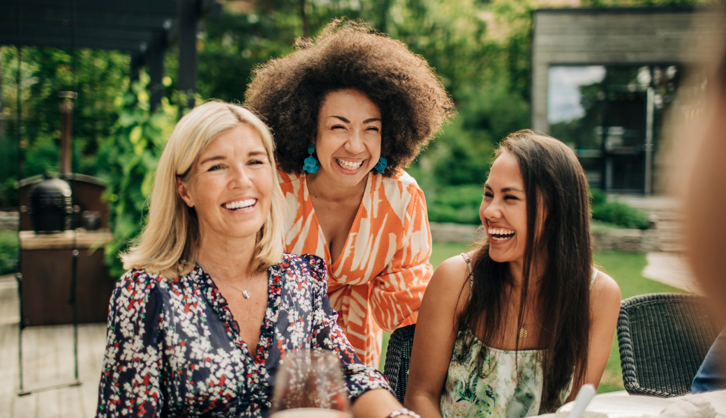 Image of three women dressed beautifully and enjoying themselves at a dinner table