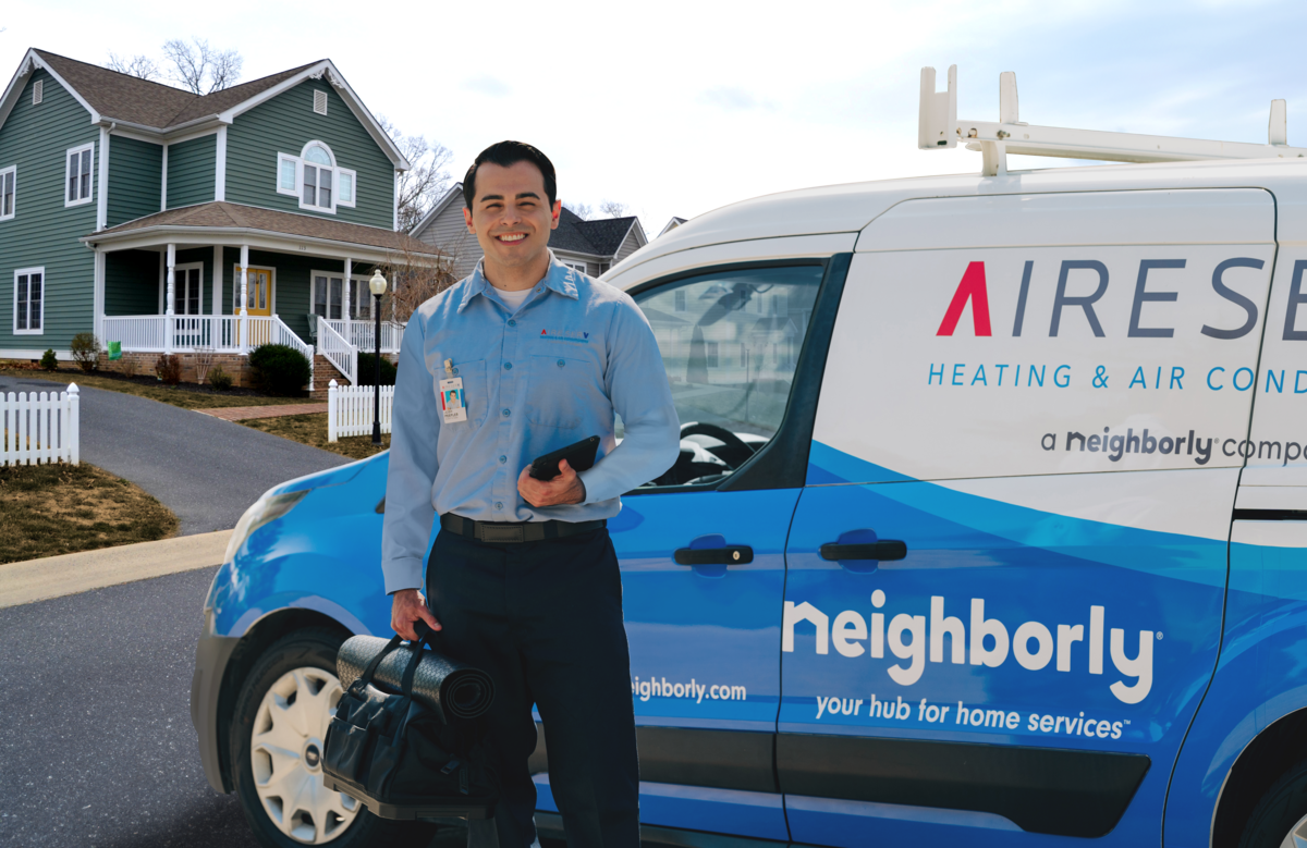 an Aire Serv tech standing on a residential street beside his Aire Serv van