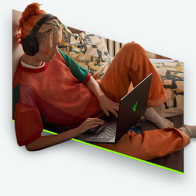 A gamer lounging on a laptop wearing a headset.