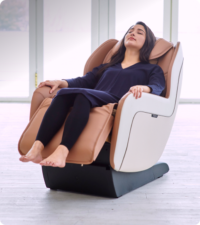 Woman in pajamas relaxing in Synca CirC+ massage chair in bright and sunny room