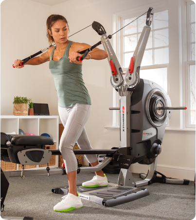 Woman doing cable chest press exercises on BowFlex Revolution Home Gym