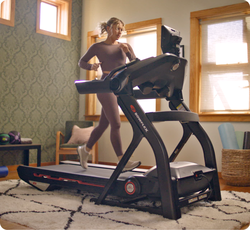 Blonde woman running on BowFlex treadmill in home bedroom