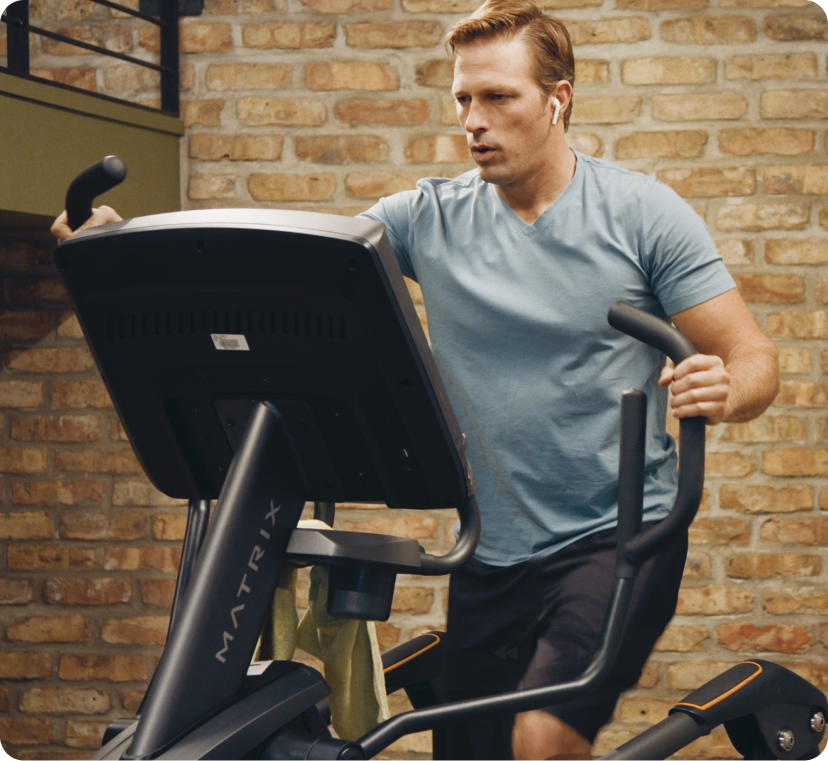 Man in blue shirt using Matrix elliptical in industrial setting