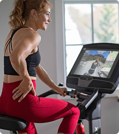 Woman exercising on Matrix Fitness Upright Bike in home gym. Woman exercising on Matrix Fitness Upright Bike in home gym.