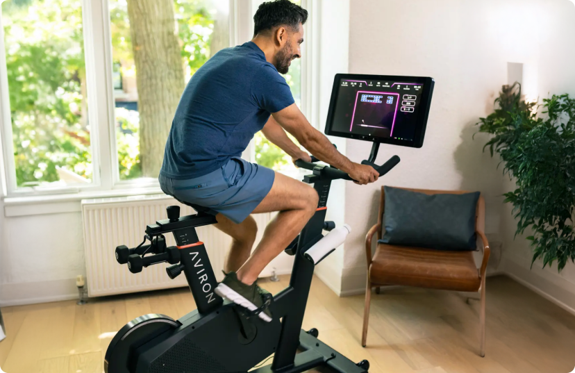 Man wearing blue riding the Aviron Fit Bike in home office
