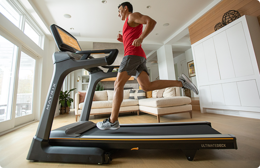 Man in red tanktop running on Matrix treadmill in large contemporary apartment Man in red tanktop running on Matrix treadmill in large contemporary apartment