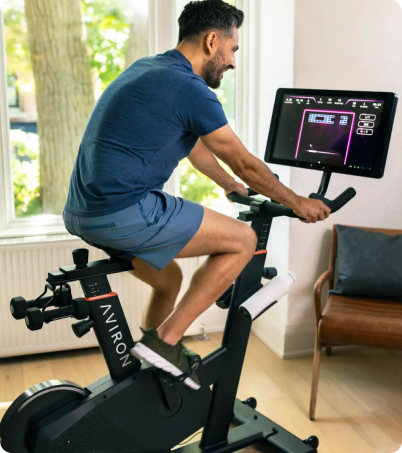 Man riding and playing games on Aviron Fit Bike at home