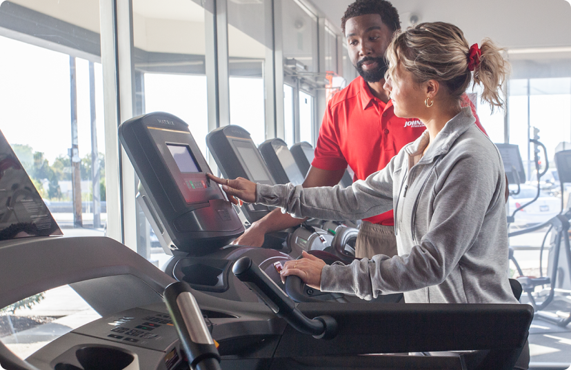 JFW employee helping female customer with treadmills in showroom JFW employee helping female customer with treadmills in showroom
