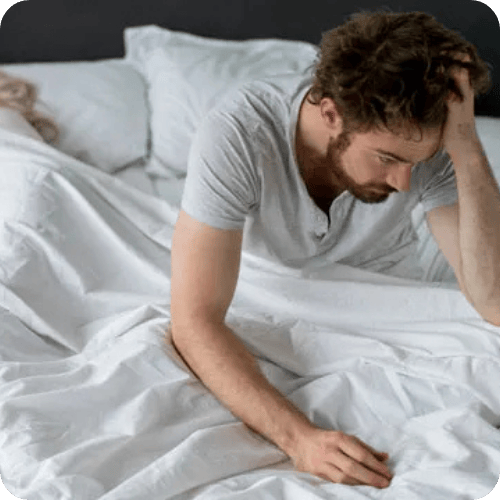 man waking up from a bad sleep while wife sleeps beside him