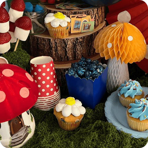 mushroom decorations, moss, a mushroom house craft, blue popcorn and cupcakes for a Smurfs party for kids