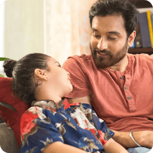 A dad talking to his daughter on the couch about her day at school