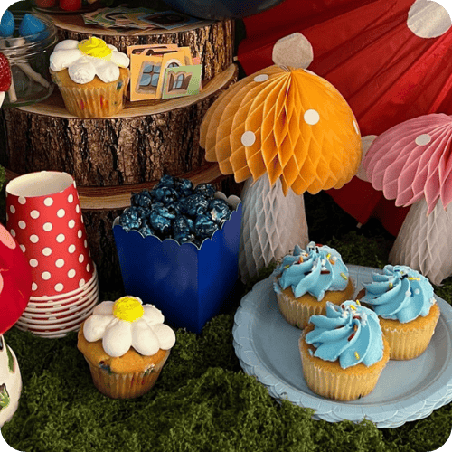 a Smurfs themed tablescape with mushrooms, moss, and treats