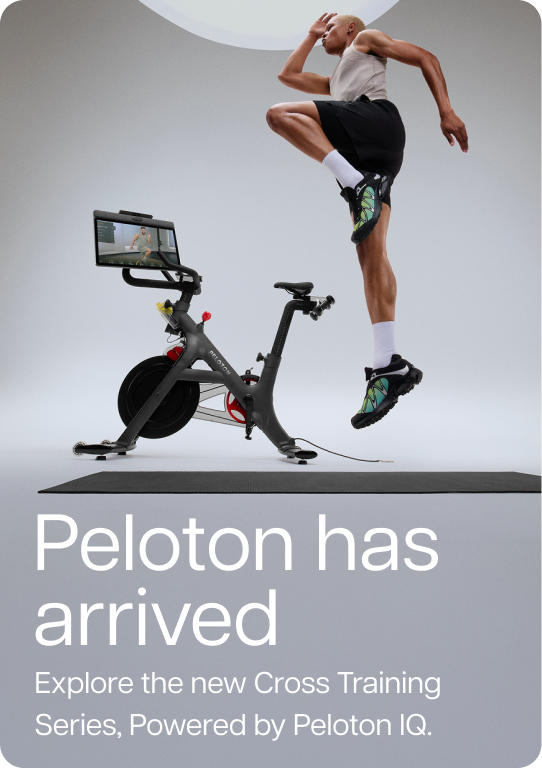 Man jumping next to Peloton Cross Training Bike+ in studio