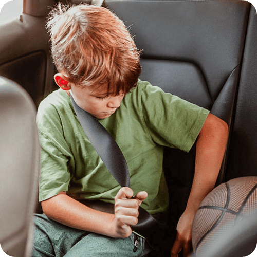 boy buckling seat belt at school pickup
