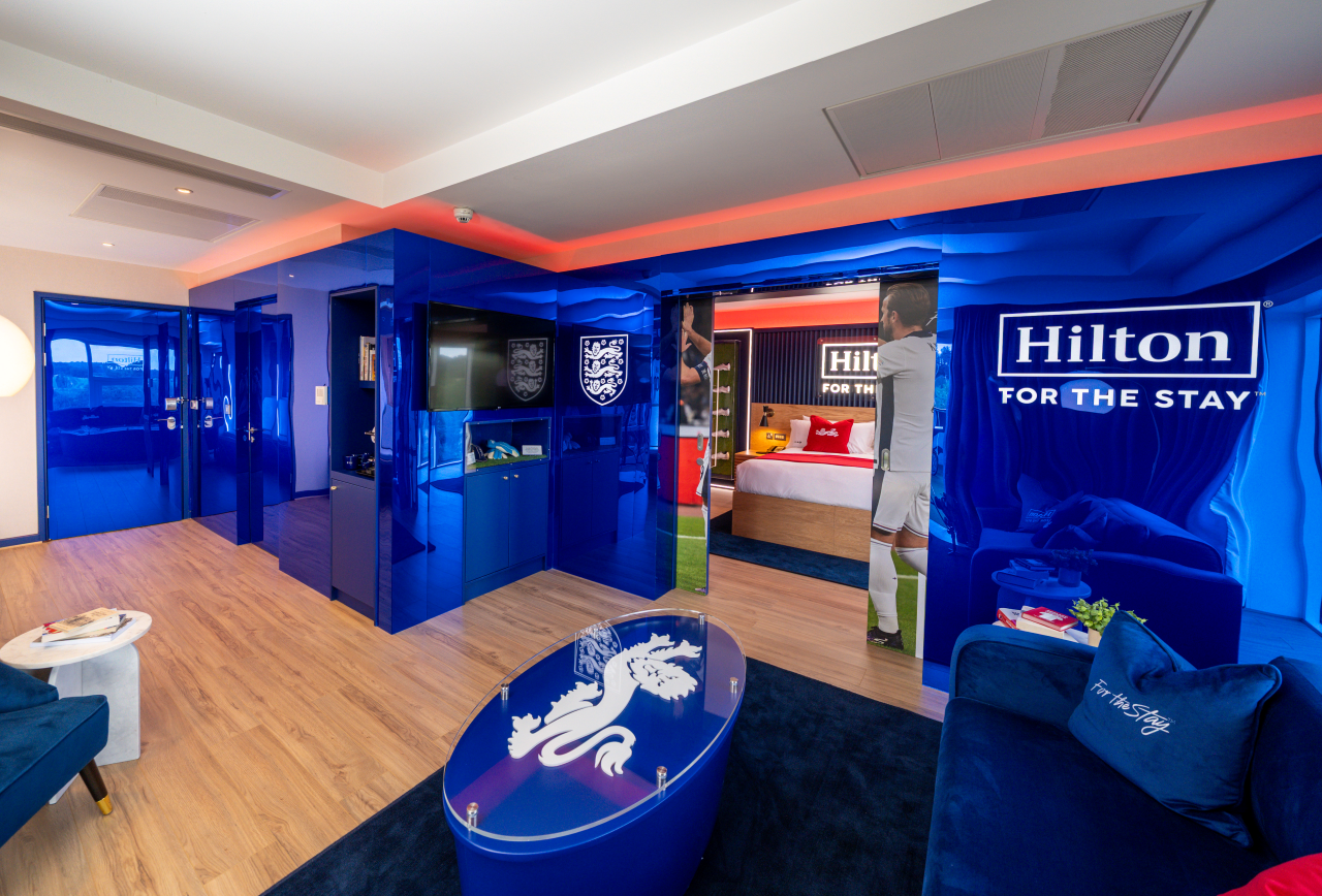 A hotel room with an England football team theme, featuring blue walls and furniture.