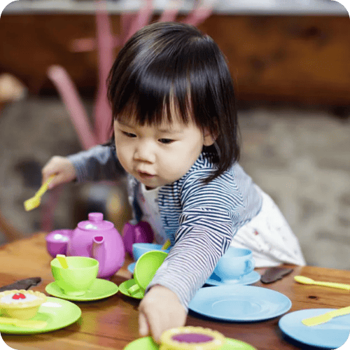 a toddler pretend playing with a tea set