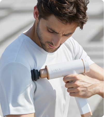 Man using Synca Kitta massage gun on his inner shoulder Man using Synca Kitta massage gun on his inner shoulder