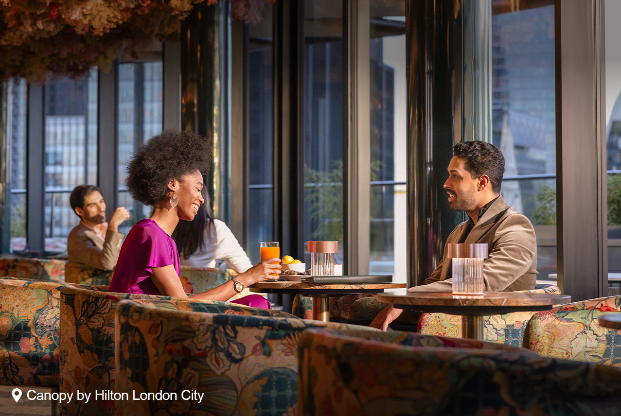 A couple sitting at a table at Canopy by Hilton London City