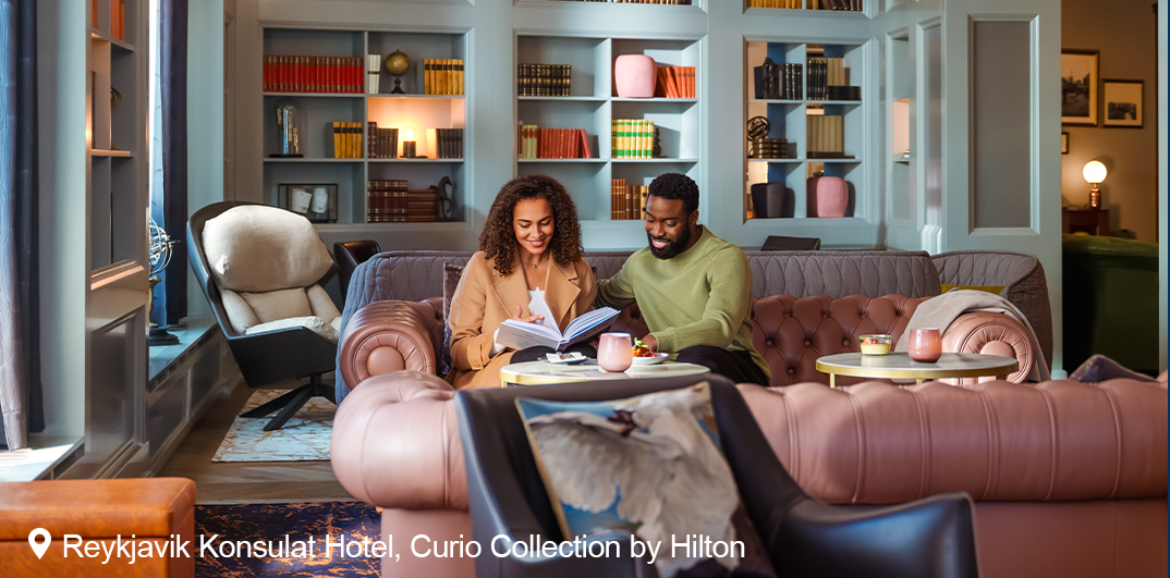 Man and woman looking at a book in a room at Reykjavik Konsulat Hotel, Curio Collection by Hilton