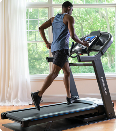 Man in blue running on Horizon Treadmill in sunny room in home