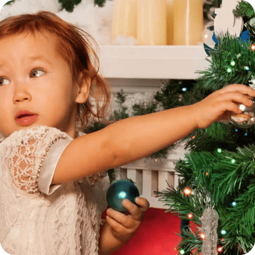 a toddler girl who is about to mess up the christmas tree