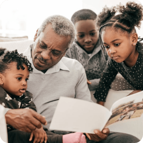 a grandfather looking through a family photo book with his grandkids