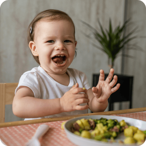 a toddler excitedly eating their dinner