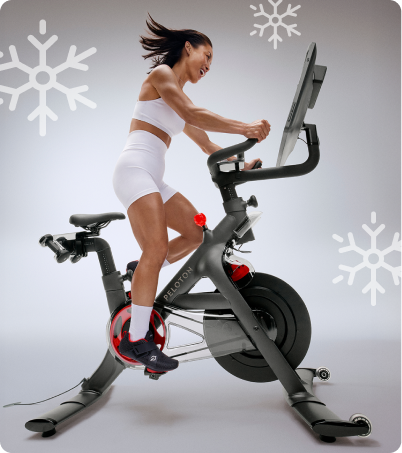 Woman riding Peloton Bike+ in gray studio
