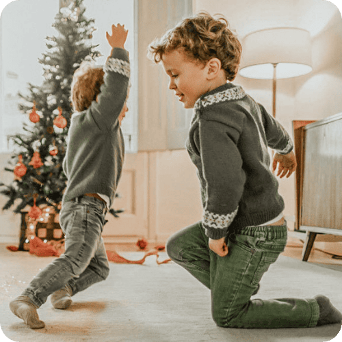 two brothers playing and making holiday memories with christmas tree in background