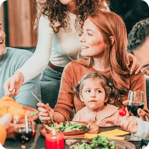 a mother with a mischievous looking toddler on her lap at a holiday meal