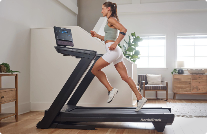 Woman in white shorts running on NordicTrack living room