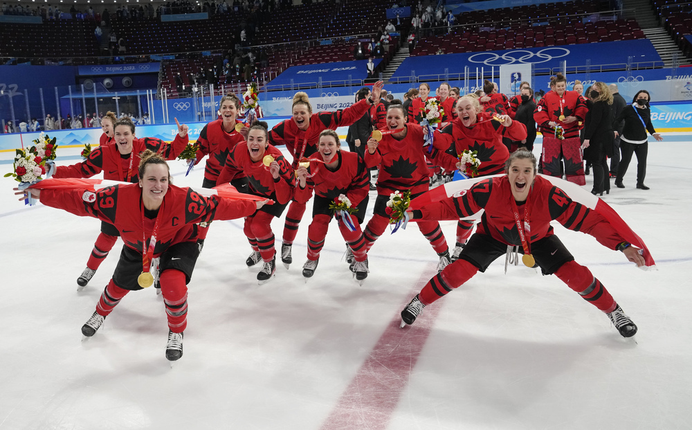 Team Canada celebrates with their gold medals after defeating the United States at the 2022 Winter Olympics in Beijing in a virtually empty stadium.