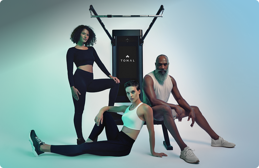 Two women and a man posing in front of Tonal 2 Smart Home Gym