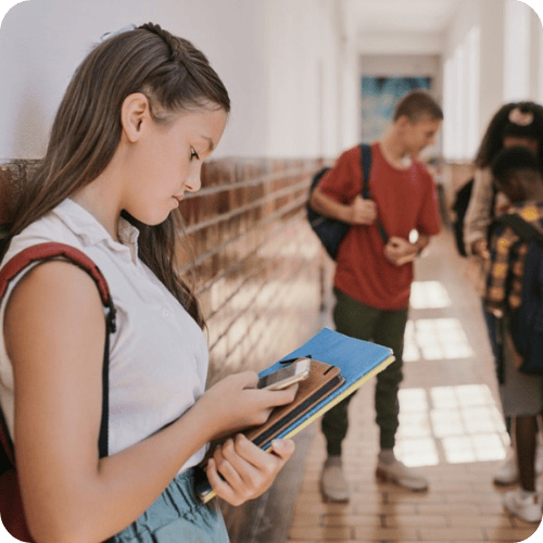 a girl looking at her phone as she's being cyberbullied