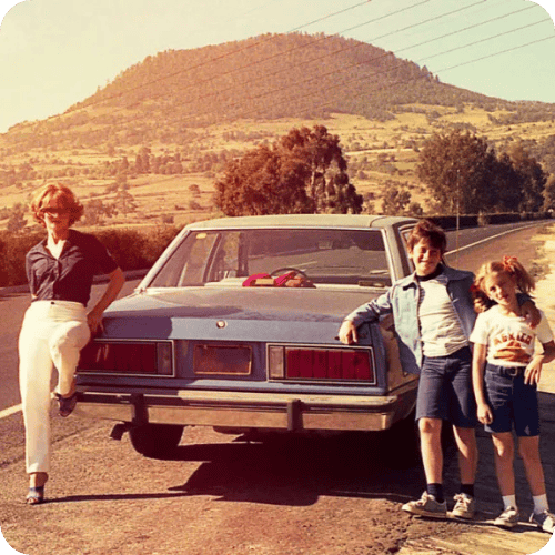 a family posing beside their car on a retro road trip