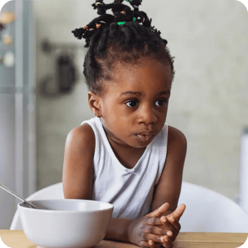 a little girl looking skeptical about her dinner