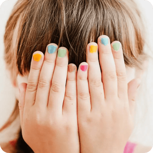 a kid covering their face with their hands that have multicolored nail polish