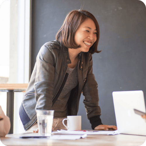 a woman smiling at work because she's not using phrases that women need to stop using