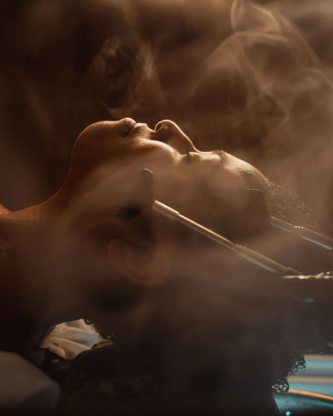 Person reclining during a head spa treatment, with steam rising as water and tools are used to massage the scalp in a calming, spa-like setting.