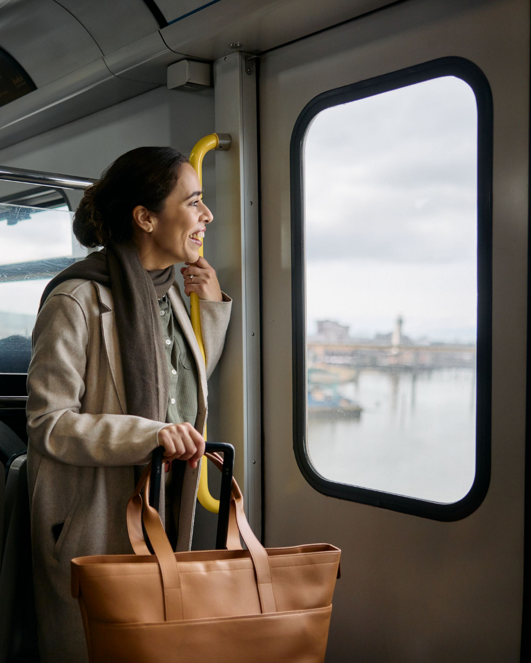 Person riding the Canada Line, looking out the window while holding a bag during the journey.