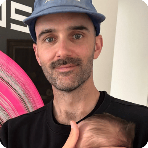 the creator @nonpracticinggenius smiling while holding his baby