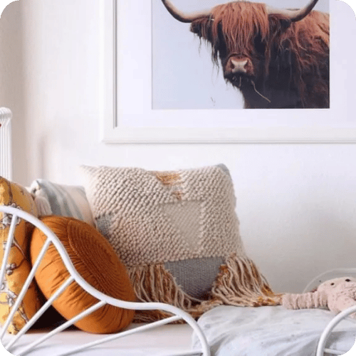 a bohemian bedroom with a large print of a highland cow on the wall