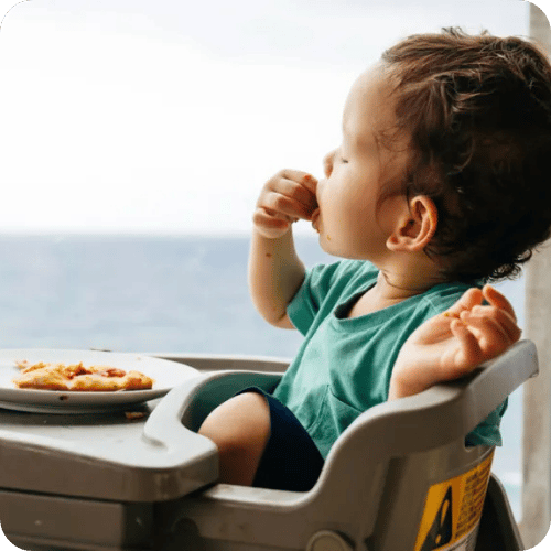 a toddler eating in his high chair