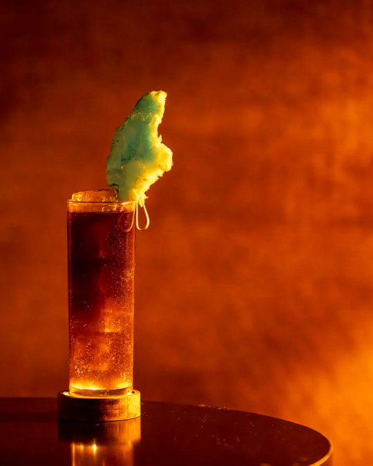 Signature cocktail at Laowai featuring a tall sparkling drink topped with cotton candy against a warm amber backdrop.