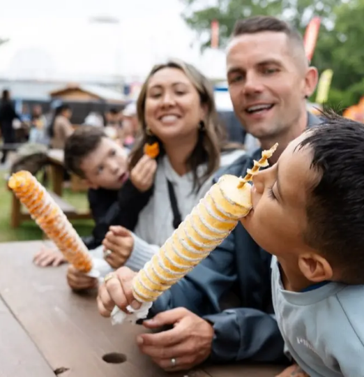 Family enjoying spiral potato snacks together at the PNE Fair in Vancouver.