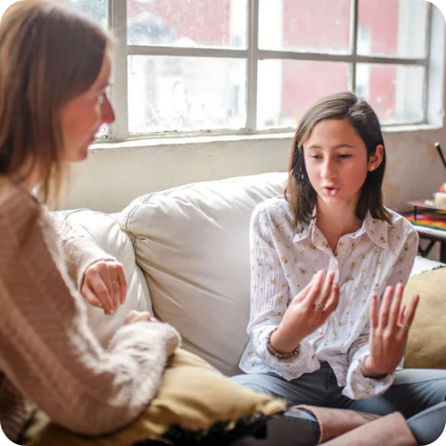 a mother and daughter talking on the couch