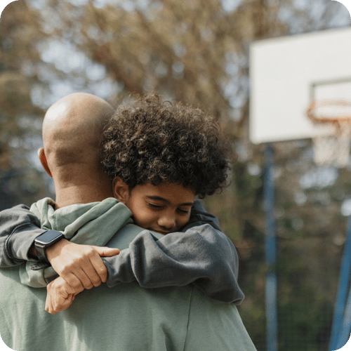 a dad and son hugging at the basketball court