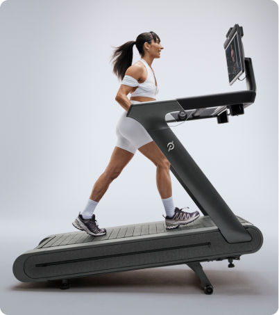 Woman wearing all white incline walking on the Peloton Tread Plus