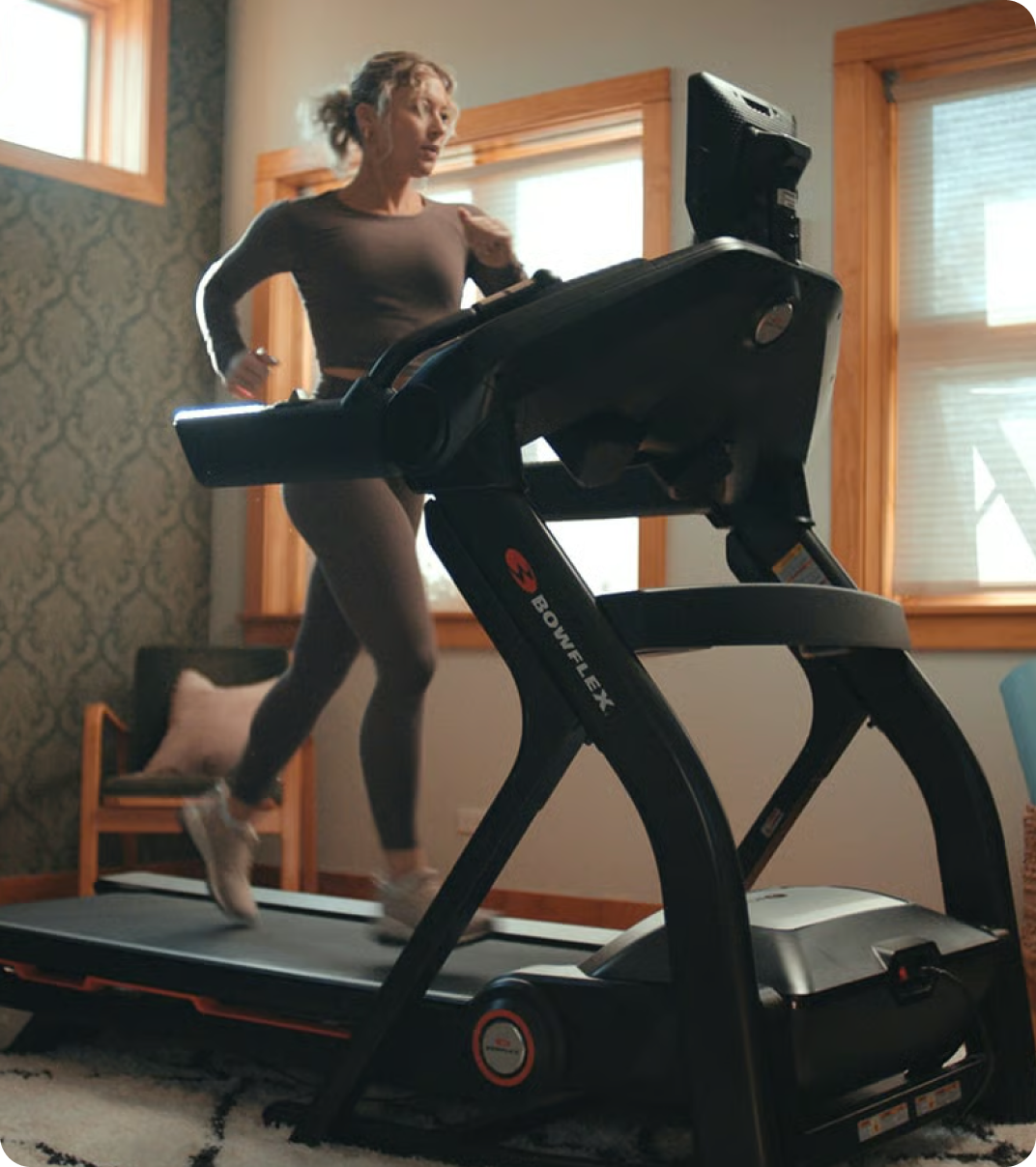 Woman enjoying a run on a Bowflex treadmill in the comfort of her home.