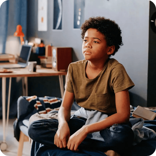 a sad kid sitting on his bed feeling defensive